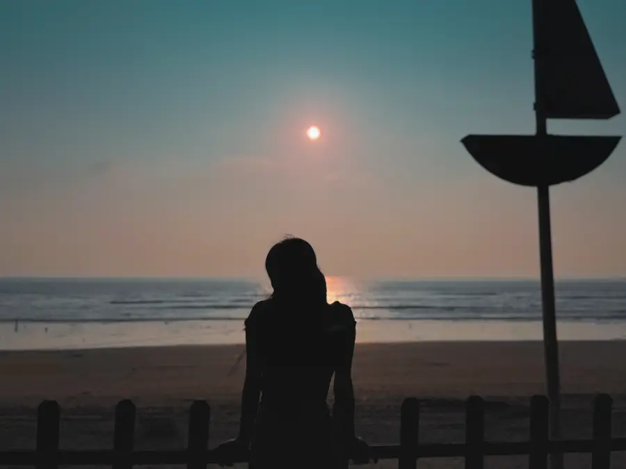 lone figure on a pier watching the sun set over the sea