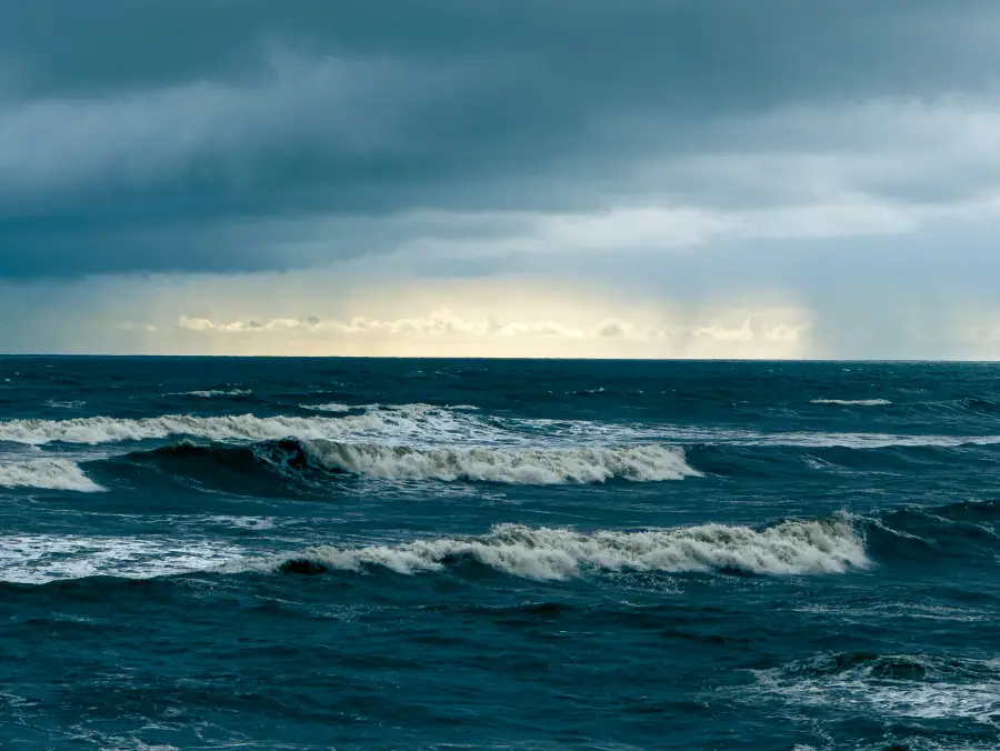 storm light over open sea and breaking waves