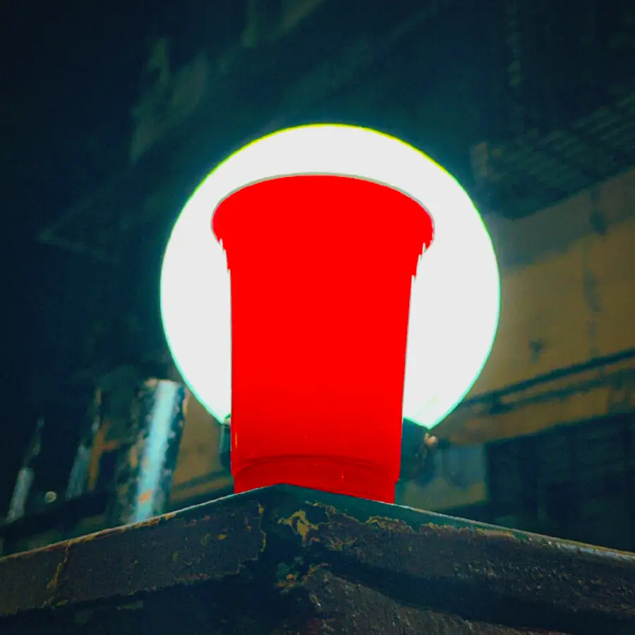 a red cup lit from behind against a rooftop sky